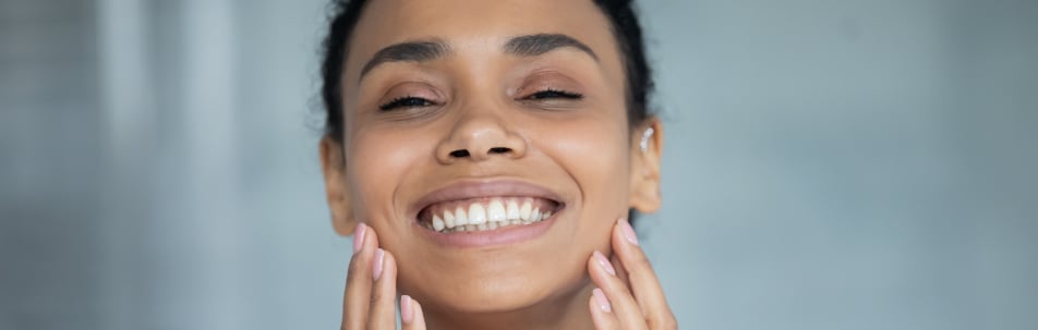 Smiling woman touching both cheeks with her hands