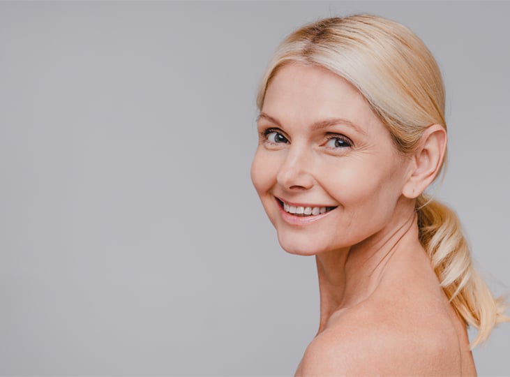 Smiling woman with blonde hair looking over her shoulder in a studio portrait