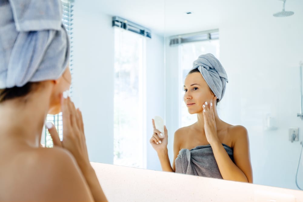 Woman in a towel wrap looking in a bathroom mirror
