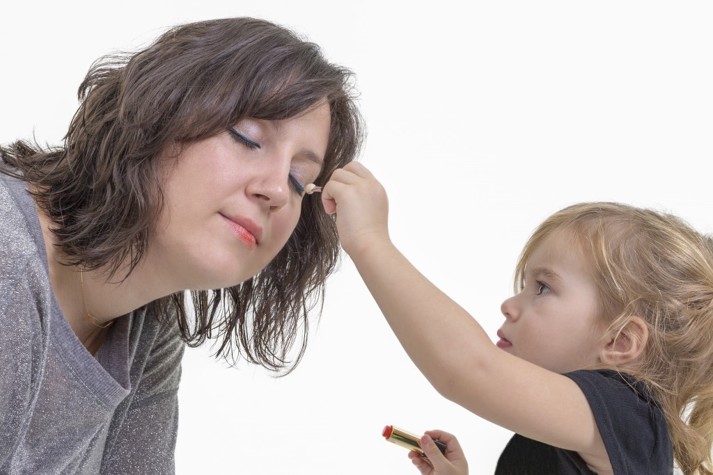 Little girl applying makeup to her mother