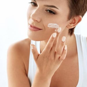 Woman applying moisturizer