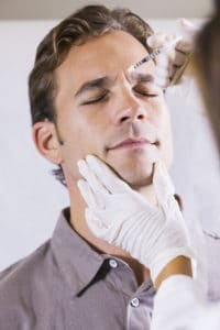 Mid adult man (30s) receiving botox injections in his forehead.