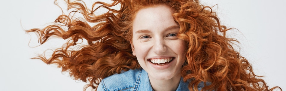 close-up image of a woman with red hair smiling at the camera