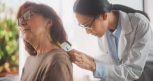 A skin cancer treatment specialist examining a patient.