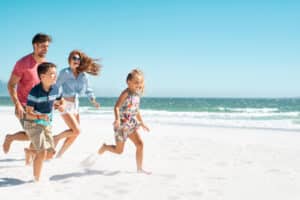 Family running on the sunny beach on 4th of July