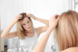 Woman checking her hair in the mirror for early signs of Alopecia Areata.