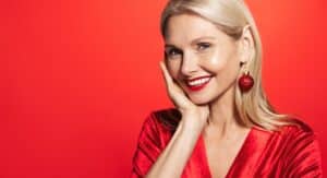 Smiling older woman touching her smooth skin while dressed for the holiday season
