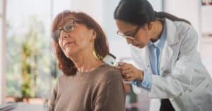 Female dermatologist inspecting woman's skin in neck area